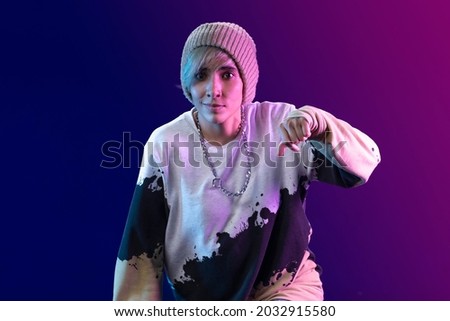 Latin woman dancing choreography in studio with casual clothes and blue background with purple
