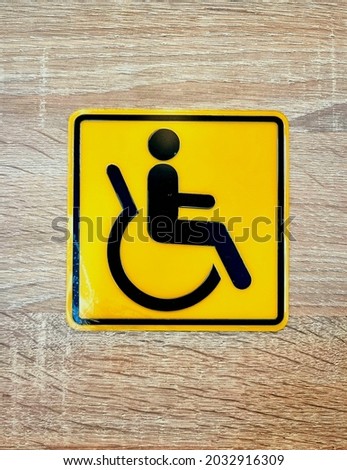 Yellow accessibility sign stick on the wooden wall. 