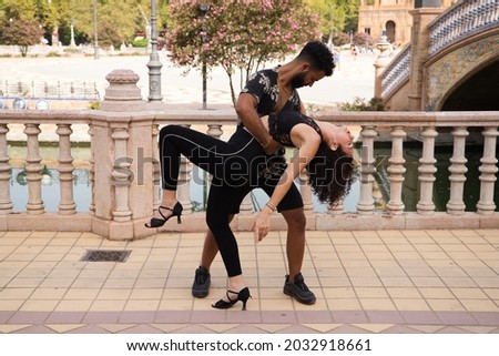 Couple of latin and bachata dancers dancing in a square. They are a young and handsome man and a beautiful woman. Dance concept Royalty-Free Stock Photo #2032918661