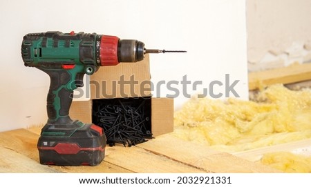 A man makes repairs in the house, a screwdriver, screws, a saw. Wooden floor.
