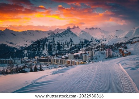 Fantastic alpine winter ski resort with buildings and beautiful mountains at dawn. Famous resort and ski slopes at sunrise, La Toussuire, Rhone Alps, France, Europe Royalty-Free Stock Photo #2032930316