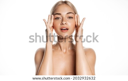 Spa and skin care. Young female model with healthy, glowing face and body, massaging using facial lotion, anti-aging cream or serum, rubbing cosmetic product with fingers, white background Royalty-Free Stock Photo #2032932632