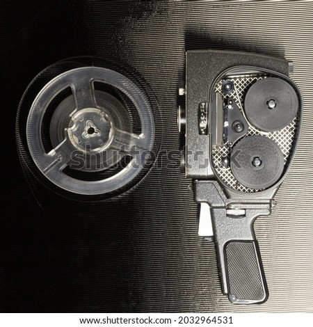 Old amateur movie camera and reel of film stock on black background