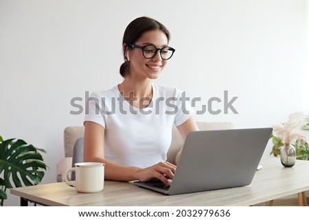 Online education concept. Young beautiful brunette woman wearing eyeglasses taking part in a group video call. Portrait of female college student studying at home. Close up, copy space, background. Royalty-Free Stock Photo #2032979636