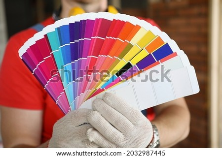 A man in gloves shows color swatches for repair