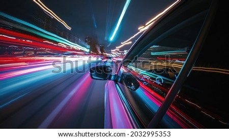 Motion time of a speedy night drive in a big city ending in the underground car parking. Side view from the car window to the road with light trails from vehicles and street lights. Royalty-Free Stock Photo #2032995353