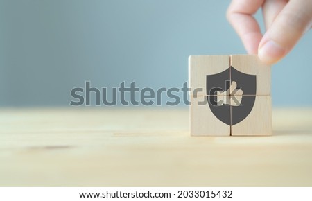 Quality warranty concept.  Man's hand puts the wooden cubes with quality warranty icon on wooden cubes with grey background. Used for banner and advertising product and service quality commitment. Royalty-Free Stock Photo #2033015432