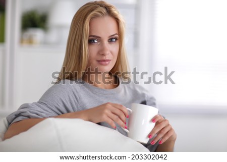 Young beautiful woman with a cup on sofa at home