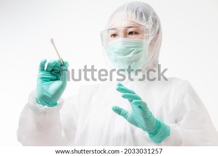 Doctor in protective suit PPE holding COVID-19 Nasal swab laboratory test. Medical worker performing Covid-19 test, taking nasal swab sample patient, PCR diagnostic, Rapid antigen test kit (ATK) Royalty-Free Stock Photo #2033031257