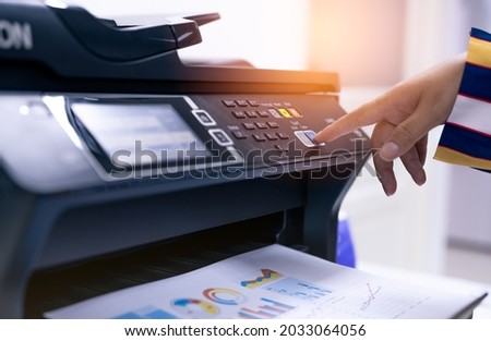Office worker print paper on multifunction laser printer. Copy, print, scan, and fax machine in office. Modern print technology.  Photocopy machine. Document and paper work. Professional scanner. Royalty-Free Stock Photo #2033064056
