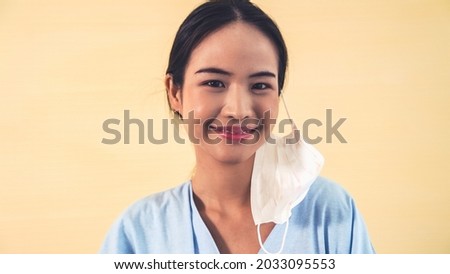 Young Asian woman take off face mask removing from face showing concept of the end of quarantine and winning over COVID-19 .