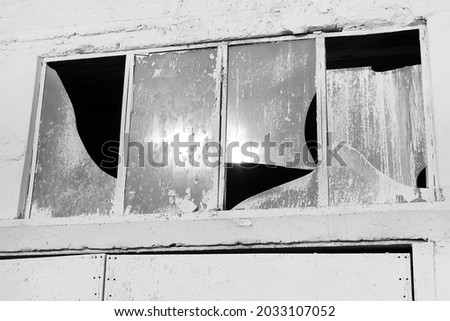Broken glass window of abandoned white facade ruined house 