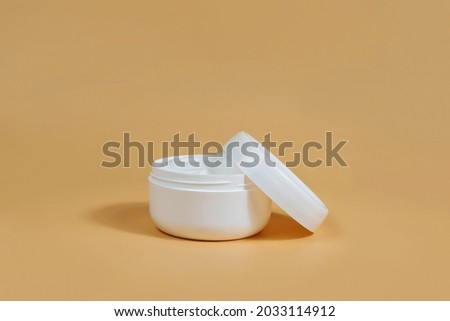Cream jar without a brand in the layout style is isolated on a beige background. Beauty background with facial cosmetics. Spa, a beauty concept