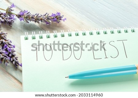 To do list, handwritten in a paper notepad, with lavender flowers on a wooden table. The concept of planning one's craft