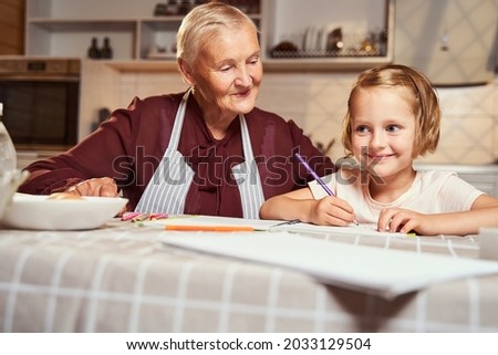 Joyful kid getting idea for picture while sitting with granny