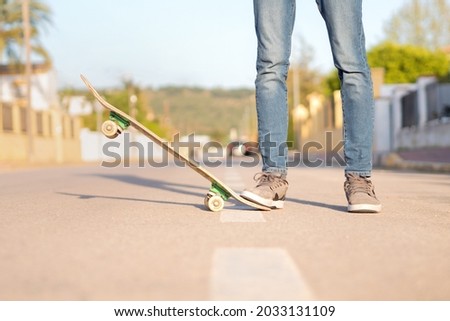 Cropped view of a young man in trainers and jeans with a skateboard. Selective focus