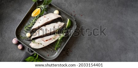 Raw halibut fish steaks with herbs and lemon prepared for cooking in a grill pan. Long banner with copy space. Healthy omega 3 unsaturated fats good for brain and mental clarity