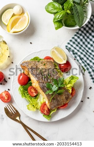 Top view of prepared delicious halibut fish steak with salad on white plate. Healthy food rich of omega unsaturated fats good for brain health