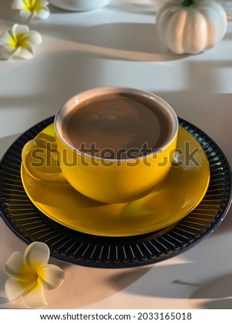 Hot chocolate in a yellow cup on the table with blurred, noise and grain editing