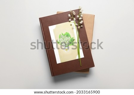Beautiful lily-of-the-valley flowers, books and greeting card on light background