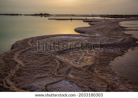  The sky merges with the sea on the horizon. Israel. Dim winter day over the Dead Sea. Evaporated salt protrudes above water. The concept of active and photo tourism