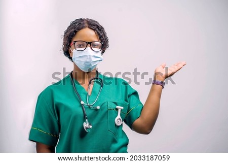 image of african health official, with face mask, stethoscope around the neck and a raised arm Royalty-Free Stock Photo #2033187059