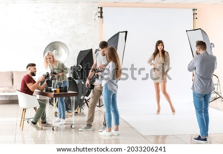 Young photographer taking picture of woman in studio