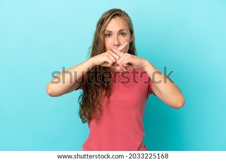 Young caucasian woman isolated on blue background showing a sign of silence gesture