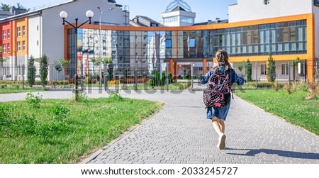 Little girl goes to the elementary school. Child with a backpack is going to study. Back to school concept. Royalty-Free Stock Photo #2033245727