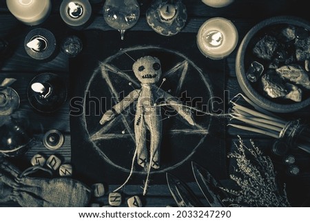 Voodoo Magic concept. Voodoo doll studded with needles with pierced rag heart on pentagram and around burning candles. Spooky or eerie magical esoteric ritual, black and white photo