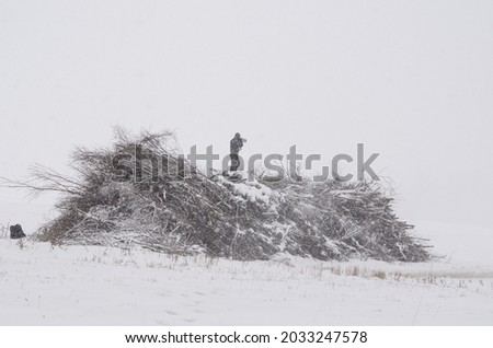The rally photographer climbed a pile of branches in winter.