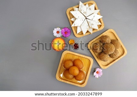 Diwali Diya, Sweets or Mithai, and flowers are arranged as a festive background. assorted sweets Kaju Katli, Gulab Jamun, and Churma laddu for Indian festivals, Ganesh Chaturthi. With copy space.