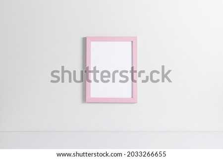 Pink photo frame mockup on white wall. Front view