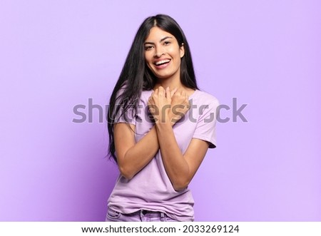 young pretty hispanic woman smiling cheerfully and celebrating, with fists clenched and arms crossed, feeling happy and positive