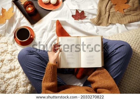 people, season and leisure concept - young woman reading book at home in autumn Royalty-Free Stock Photo #2033270822