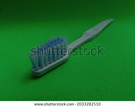 white toothbrush with blue and white bristles isolated on green background