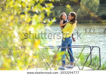 mother and child standing near beautiful lake