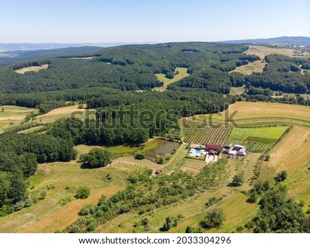 Aerial view of remote house with swimming pool, lake and orchard. Summer 2021
