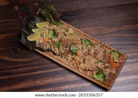 Pork fried rice with broccoli and carrots on wooden background.