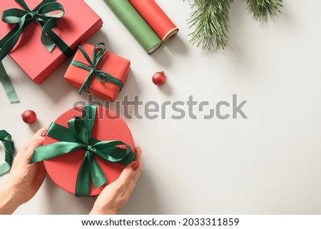 Woman wrapping gift boxes for Christmas in red and green wrap paper for holidays. View from above. Banner.