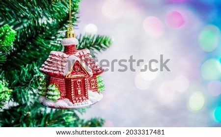 Christmas decoration on a branch of a tree on a defocused colored background with bokeh and copy space.