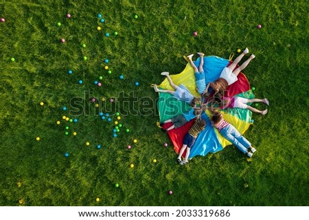 Group of children with teachers holding hands together on rainbow playground parachute in park, top view. Summer camp activity Royalty-Free Stock Photo #2033319686