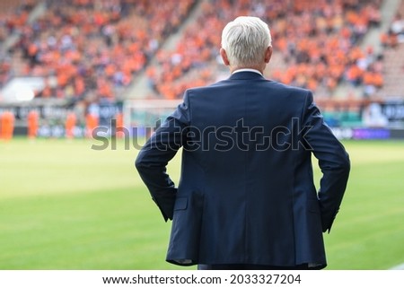 Head coach's back and soccer match at the stadium in the background Royalty-Free Stock Photo #2033327204
