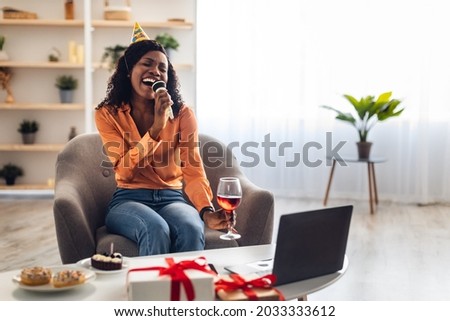 Birthday Party Via Video Call. Black Woman At Laptop Singing Karaoke Celebrating Her B-Day Online With Distance Friends Sitting In Living Room Indoors. Holiday Celebration. Selective Focus