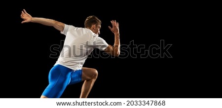 Flyer. One muscular, sportive man, male athlete, runner training isolated on dark studio background with spotlight. Concept of action, motion, youth, healthy lifestyle. Copyspace for ad.