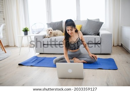 Portrait of young sport woman with laptop doing exercise indoors at home, healthy lifestyle concept.