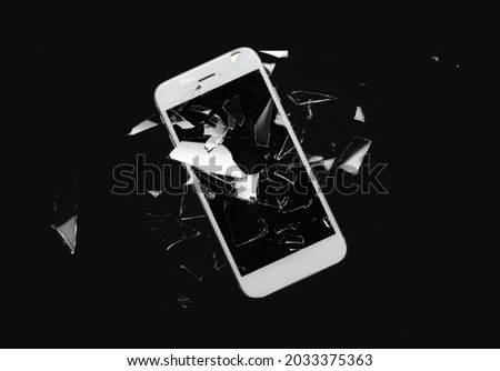 Mobile phone with cracked glass screen on dark background