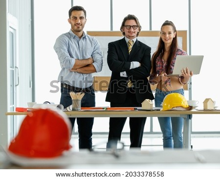 Three businesspeople, female secretary, a boss in formal suit and male engineer standing together in office and pose for photos. Idea for teamwork in the company. Idea for teamwork concept.