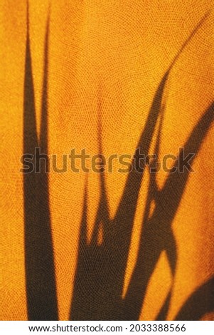 Palm leaf shadow on yellow textured fabric