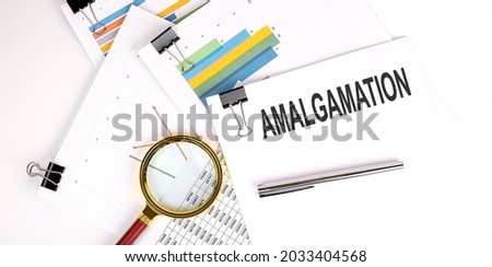 AMALGAMATION text on white paper on light background with charts paper